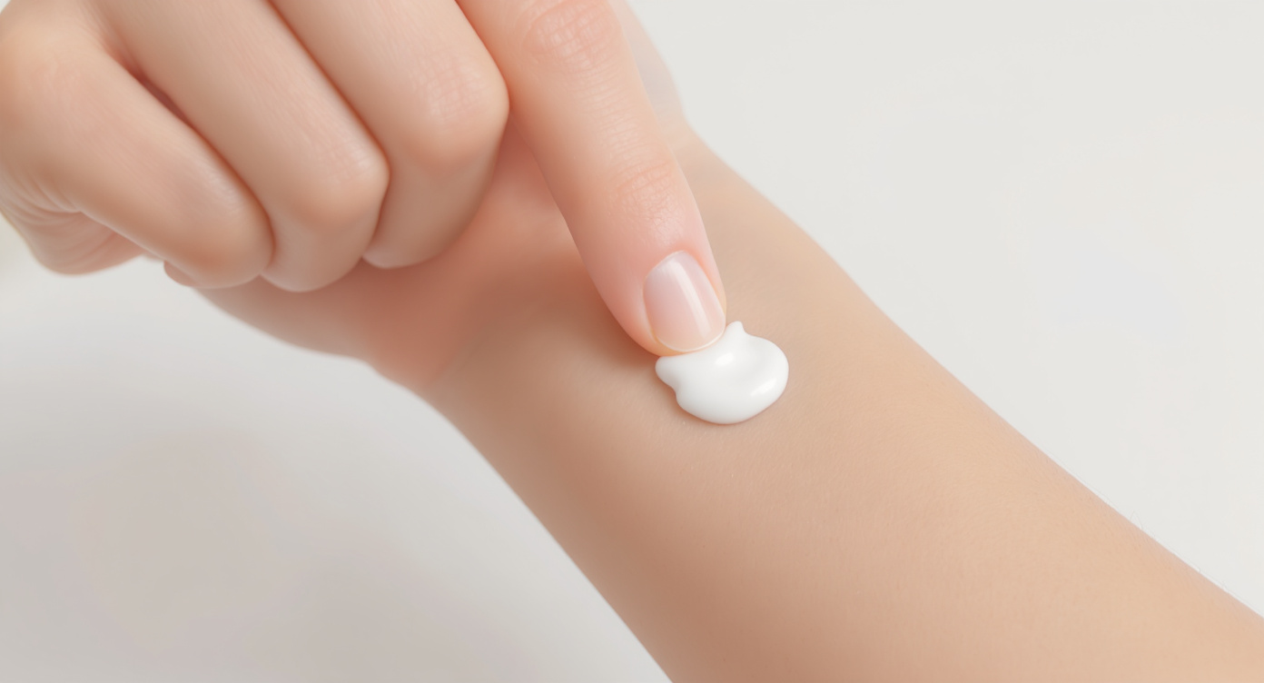 A person applying doctor-prescribed ointment to a healing spot on their arm after a skin procedure.