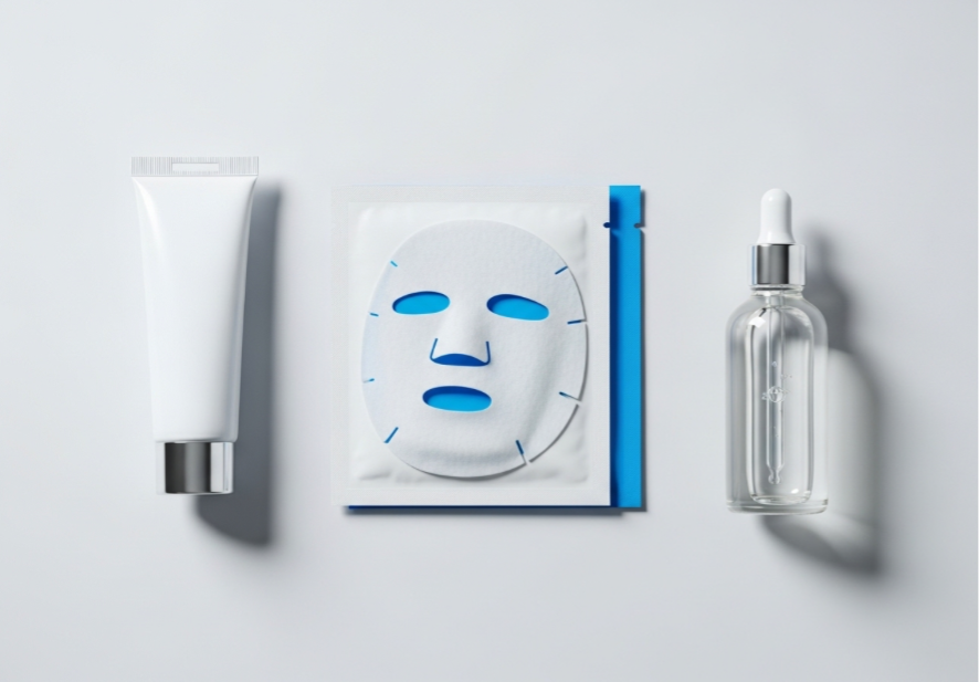 A clean, flat-lay arrangement of post-treatment skincare products, including a tube of healing ointment, a medical-grade face mask, and a bottle of saline solution on a sterile background.