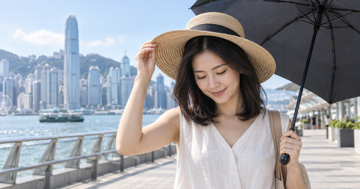 Asian woman protecting her scalp from the Hong Kong sun with a wide-brimmed hat and umbrella.